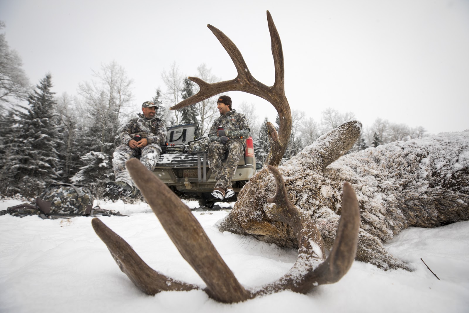 Whitetail hunters share stories with a buck on the ground.