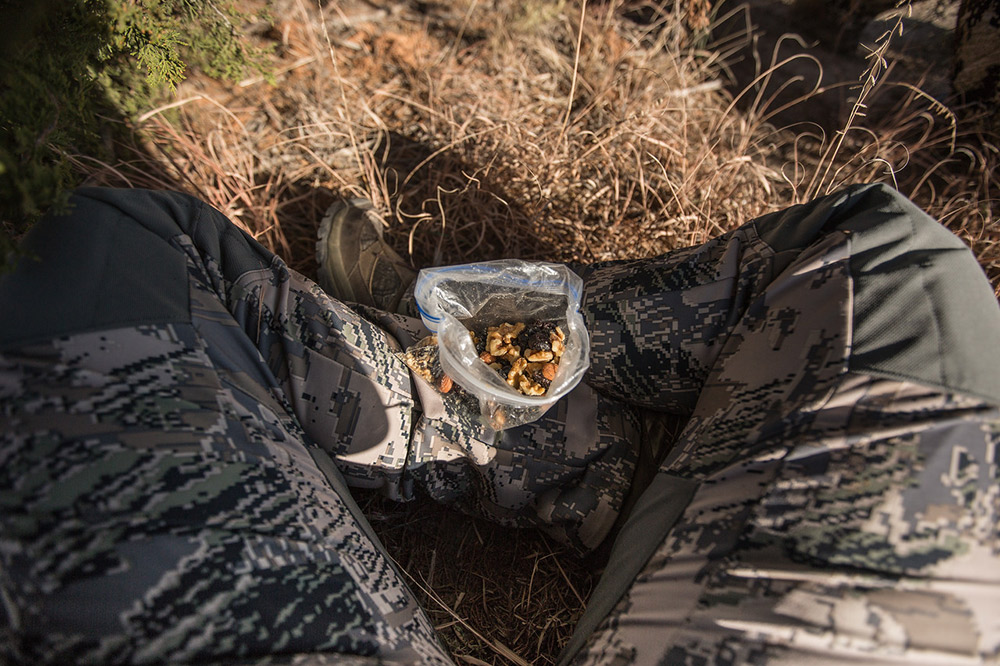 A hunter enjoys a snack bag of trail mix for backcountry nutrition.