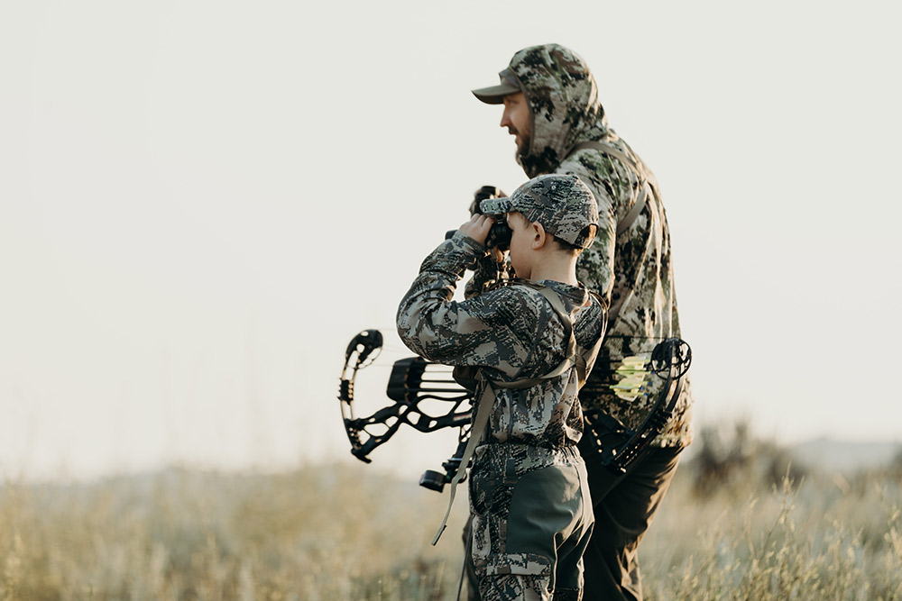 Father and son spy on antelope as they discuss their stalk.