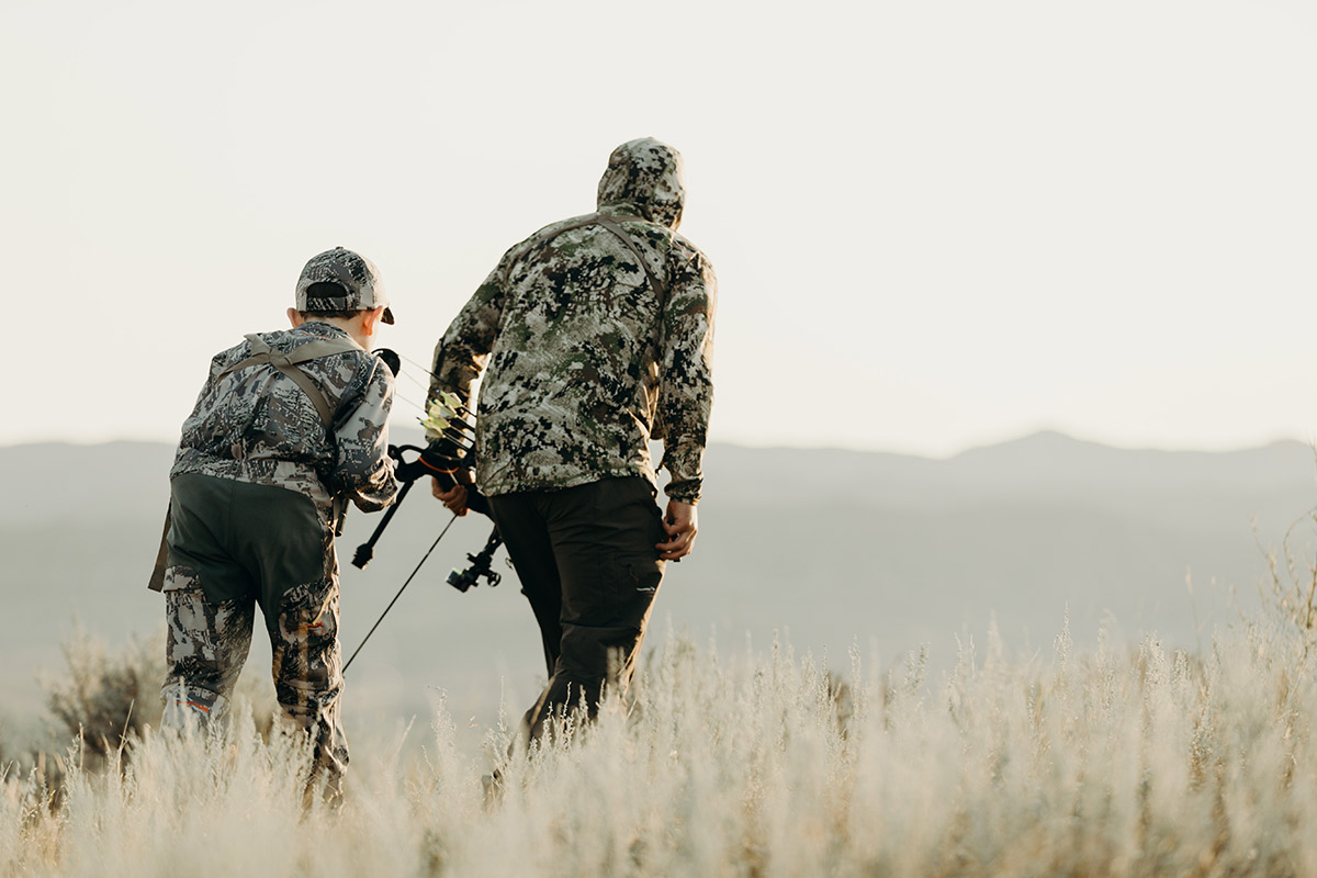 Father and son stalk antelope in sagebrush.