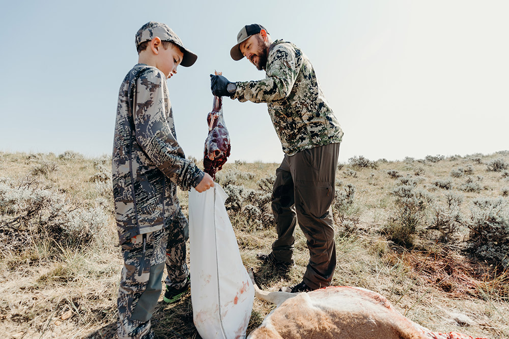 A father and son field dress an antelope after a successful hunt.