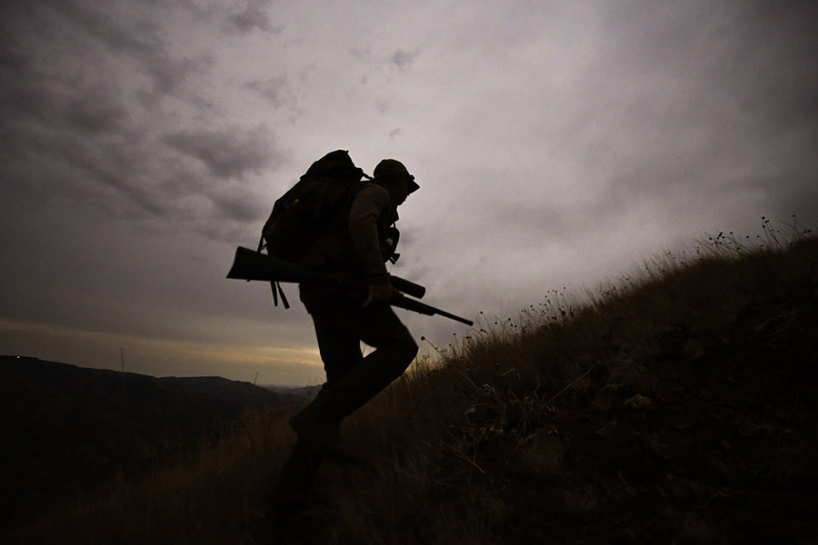 A big game rifle hunter hikes into his spot.