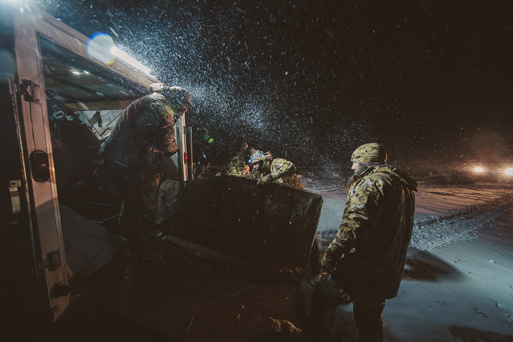 Goose hunters unloading their trailer full of decoys and blinds in heavy snow.