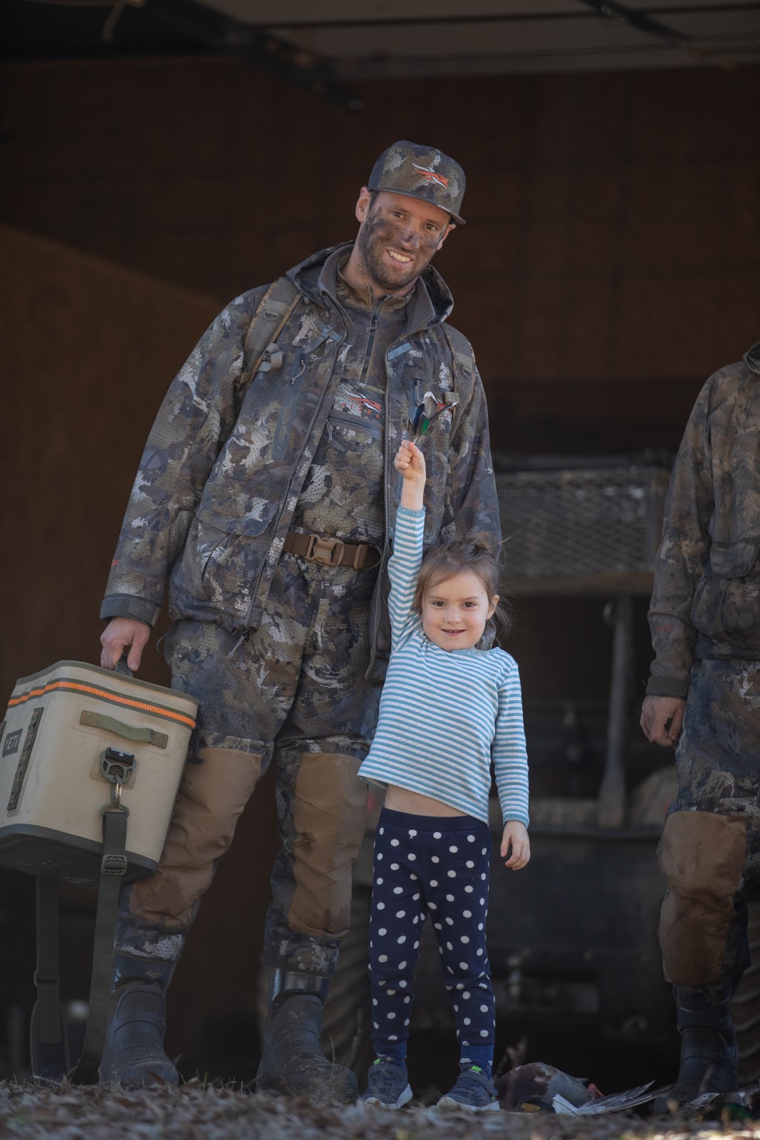 Father and daughter post-duck hunt. Yeti cooler in tote.